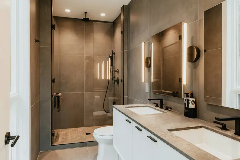 Bathroom with a double vanity and a tiled walk-in shower behind glass