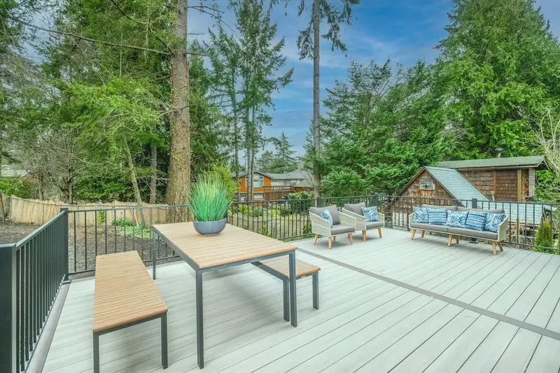 Light gray deck with a wooden table, benches and outdoor seating
