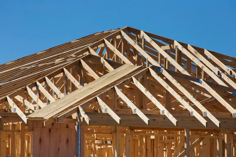 Wood roof framing of a new house against a blue sky