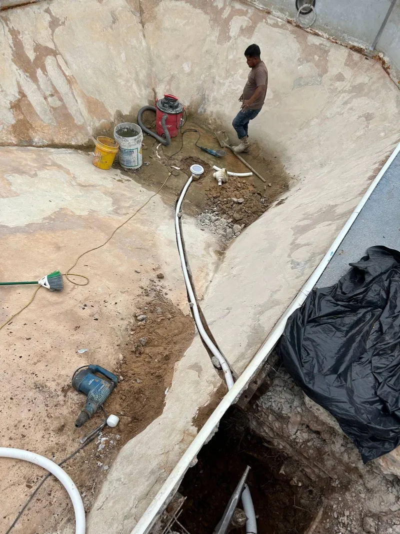 New white PVC line laid in the floor trench from the deep end drain to the pool wall